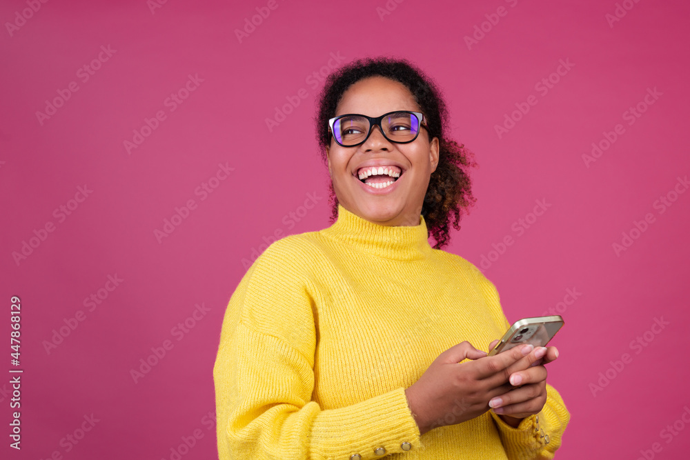 Beautiful african american woman on pink background typing message on mobile phone excited happy smile and laugh Beautiful african american woman on pink background typing message on mobile phone excited happy smile and laugh