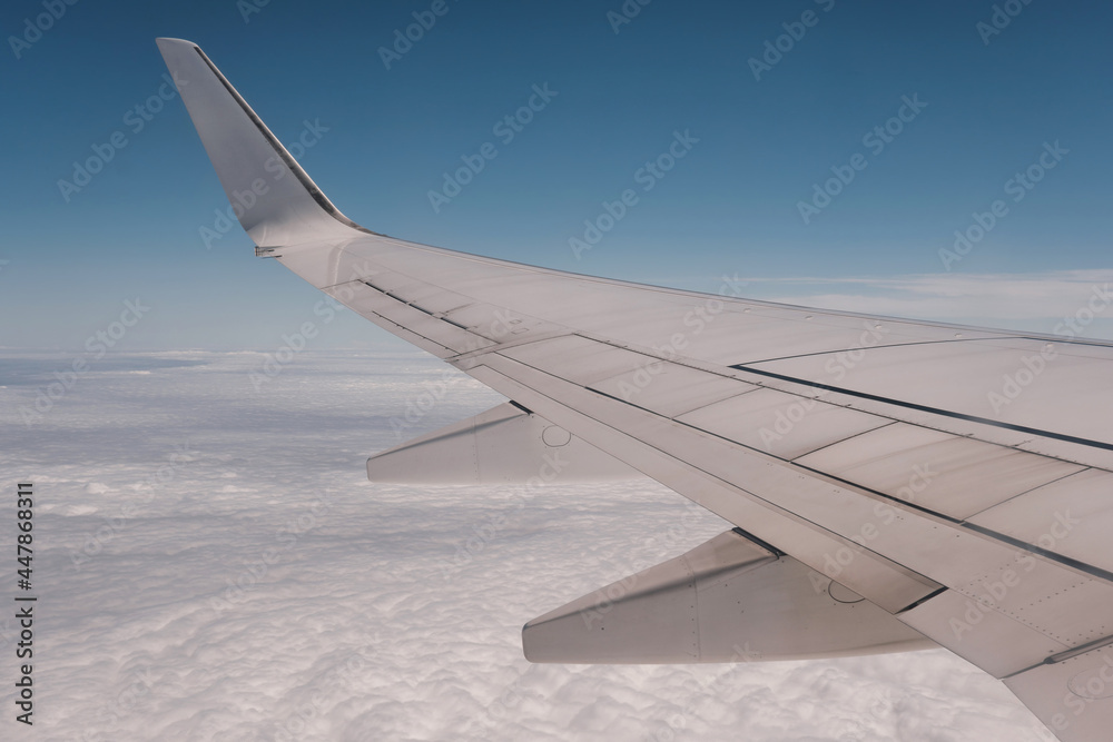 Obraz premium View of an airplane wing above the clouds on a sunny day.
