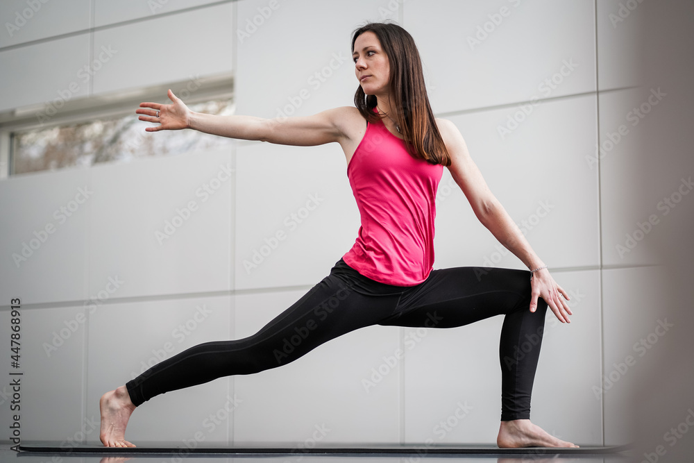 trained brunette woman in black leggin stretching slim body while practicing warrior 2 yoga pose indoor in a white modern studio on a mat
trained brunette woman in black leggin stretching slim body while practicing warrior 2 yoga pose indoor in a white modern studio on a mat