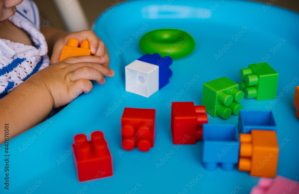 Obraz premium The child collects a multi-colored constructor. Children's classes in kindergarten or at home.