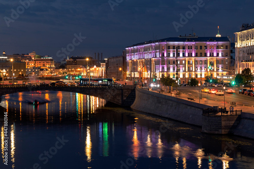 A river in front of a Moscow cityscape against a sky at summer night
