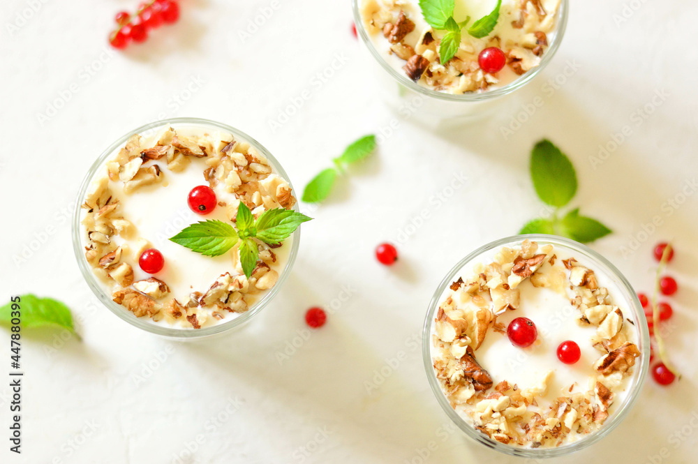 Dessert in a glass on a light background, decorated with nuts, mint leaves and berries. Creamy jelly. Parfait. Dessert in a glass on a light background, decorated with nuts, mint leaves and berries. Creamy jelly. Parfait.
