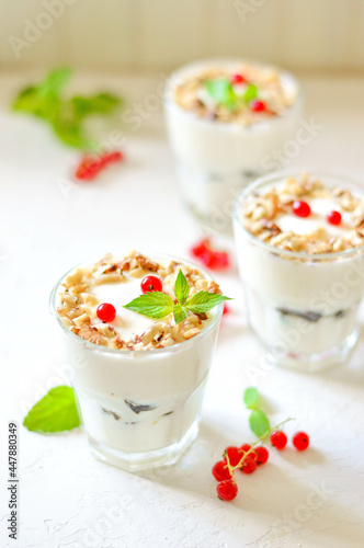 Dessert in a glass on a light background, decorated with nuts, mint leaves and berries. Creamy jelly. Parfait.