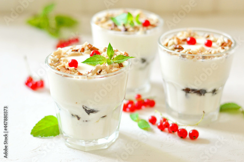 Dessert in a glass on a light background, decorated with nuts, mint leaves and berries. Creamy jelly. Parfait.