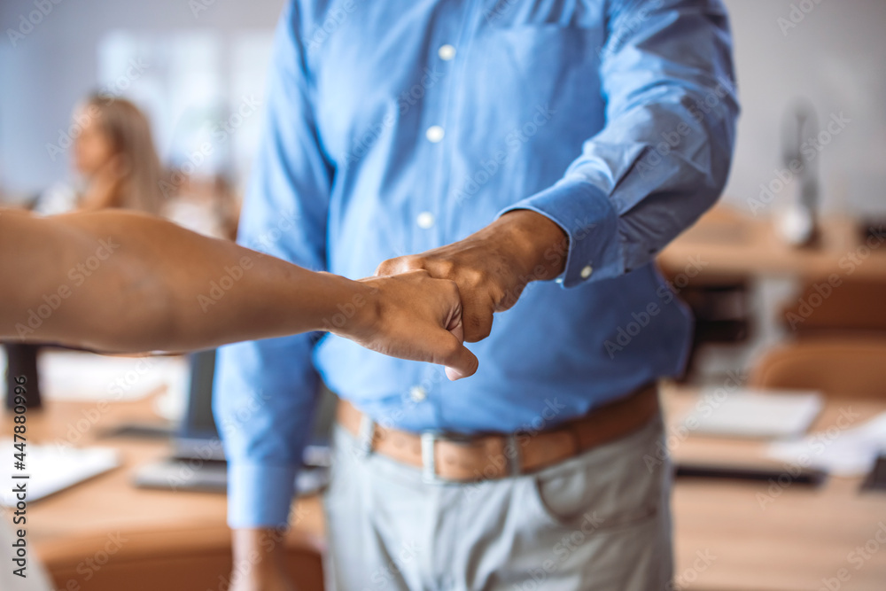 Fototapeta premium Partner trust business partnership mission deal. Businessman fist bumping with a colleague in the office. Close up of businessmen fist bumping in the office.