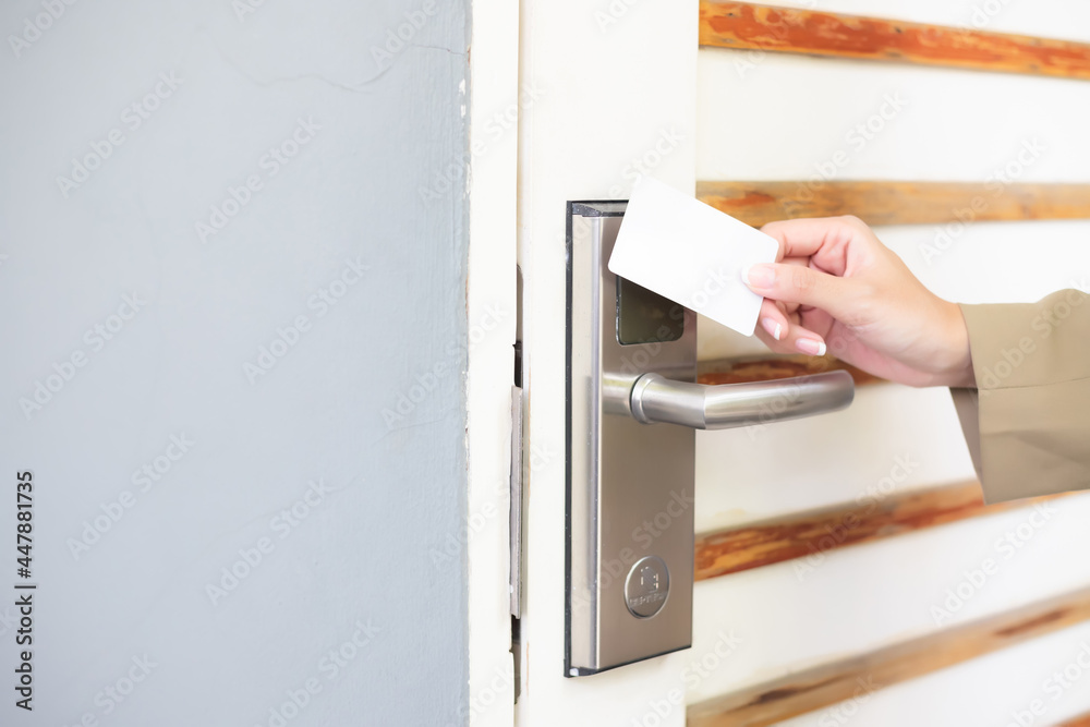 Hand holding the key card, touching the door to unlock and enter the hotel room or apartment. Hand holding the key card, touching the door to unlock and enter the hotel room or apartment.