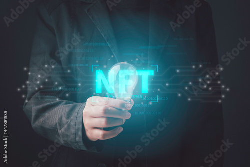 NFT non fungible tokens concept. Businessman holding light bulb idea creativity with digital unique art NFT hologram on circuit board