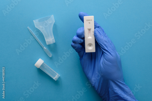 Hand in protective glove showing negative antigen covid test with pipette and saliva photo