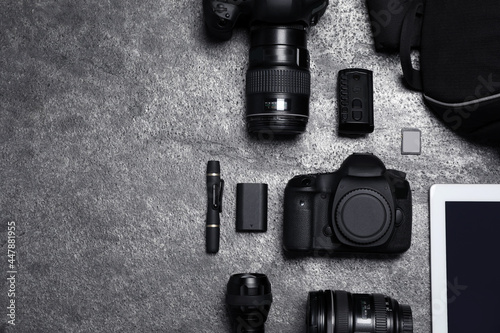 Professional photography equipment and backpack on grey stone table, flat lay. Space for text photo