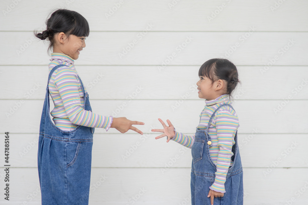 Two Children playing in a rock-paper-scissors game on white background Two Children playing in a rock-paper-scissors game on white background