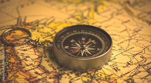 Old compass on a vintage world map, selective focus, cartography and geography concept background © FellowNeko