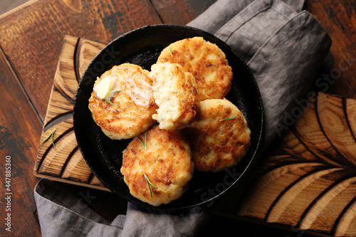 Fish cutlets (meatballs), in a cast-iron pan, with a slice of butter, decorated with rosemary leaves. view from above.