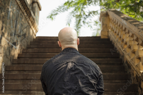 Quadro em tela Back view of a bald beefy Caucasian man standing in front of the stairs