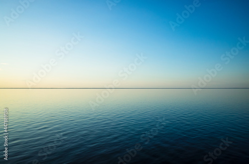 Tranquil minimalist landscape with a smooth blue sea surface with calm waters with a horizon and clear skies. Simple beautiful natural calm background. Copy space. photo