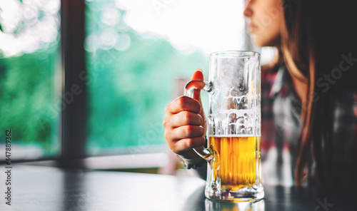 woman holds a glass of beer in his hand at the bar or pub