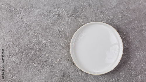 Empty white plate on gray concrete background