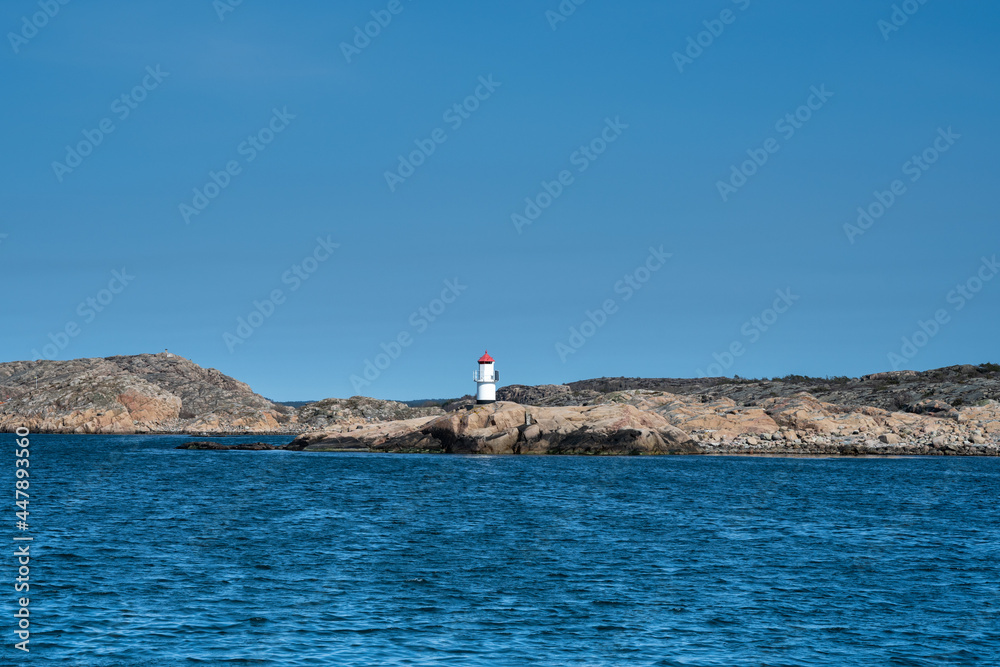 A picture of a beautiful rock island. Ocean and blue sky in the background. Picture from the Weather Islands, on the Swedish West coast