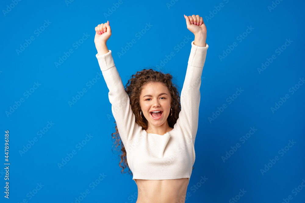 Successful young woman feeling very excited and raising her arms