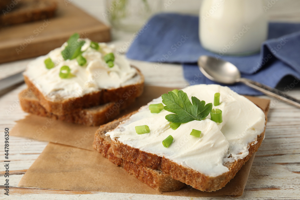 Bread with cream cheese, green onion and parsley on white wooden table, closeup Bread with cream cheese, green onion and parsley on white wooden table, closeup