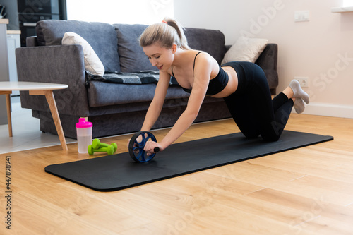Woman do exercise with wheel roller on fitness mat