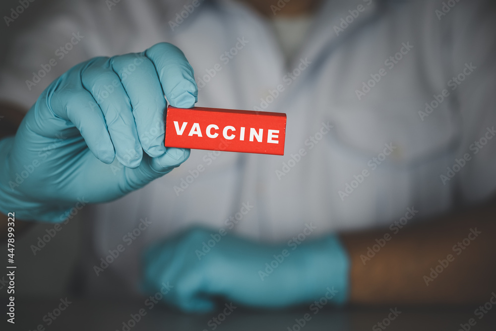 A doctor or scientist medical holds a wooden red stick with text vaccine A doctor or scientist medical holds a wooden red stick with text vaccine