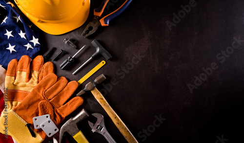 Happy Labor day concept. American flag with different construction tools on dark stone background. © Siam