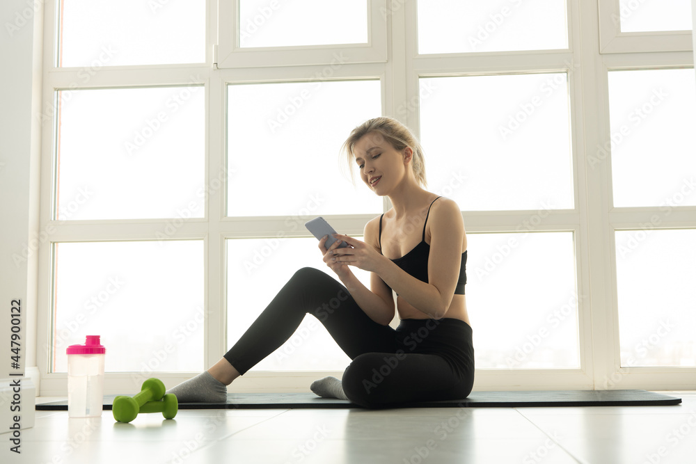 Sportswoman using mobile phone on fitness mat Sportswoman using mobile phone on fitness mat