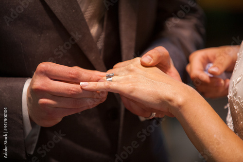 Close up of loving bride and groom putting a beautiful wedding ring to the beloved partner, marry me concept. High quality photo