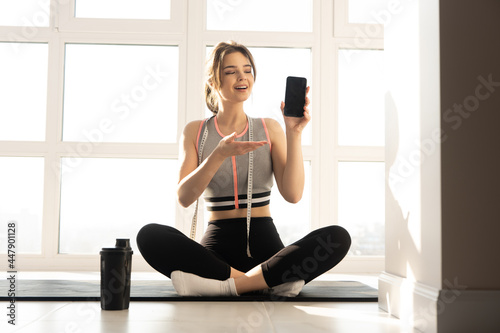 Sportswoman showing mobile phone on fitness mat