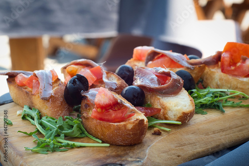 Delicious Croatian appetizer - toasted bruschetta bread with tomato, anchovies, arugula, olives and cheese