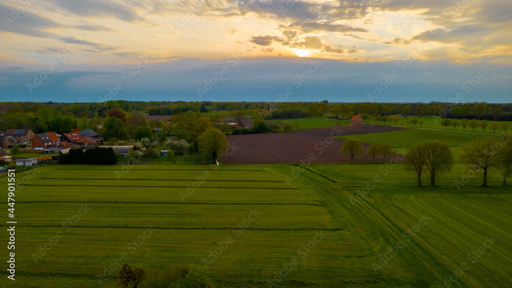 Fototapeta premium Aerial photo of agricultural fields with beautiful sunset with sun rays taken with a drone. High quality photo