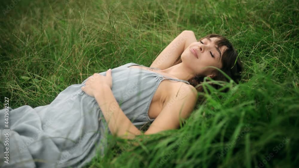 Happy Smiling Young Woman falling down on the green grass. Beautiful young woman lying on the field. Fresh natural summer concept. View from the top Happy Smiling Young Woman falling down on the green grass. Beautiful young woman lying on the field. Fresh natural summer concept. View from the top