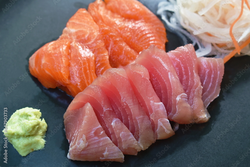 slice raw tuna and salmon fish sashimi Japanese food with radish on plate dipping shoyu or soybean sauce couple wasabi slice raw tuna and salmon fish sashimi Japanese food with radish on plate dipping shoyu or soybean sauce couple wasabi