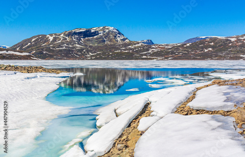 Frozen turquoise lake Vavatn panorama in summer landscape Hemsedal Norway.