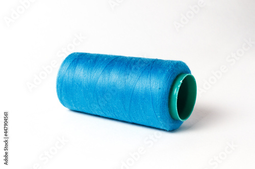 A large bobbin of blue thread on a white background