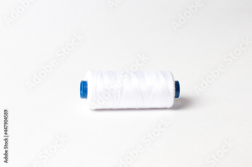 A spool of white thread. White background.