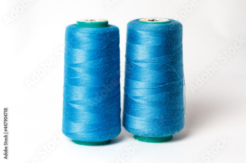 A large bobbin of blue thread on a white background