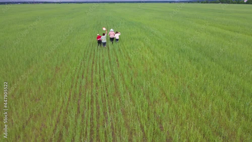 A happy family is running amicably and cheerfully on a green field. Friendly family vacation, nature hike from a bird's eye view. People spend their time in the open air carefree. There is copy space A happy family is running amicably and cheerfully on a green field. Friendly family vacation, nature hike from a bird's eye view. People spend their time in the open air carefree. There is copy space