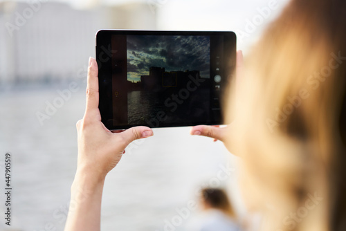 Cropped female tourist using modern touch pad and main camera for clicking image photos during travel vacations and sightseeing, woman photographing landscape via application on digital tablet