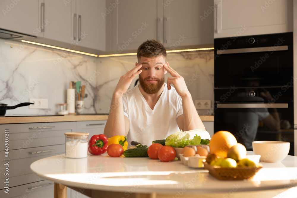 Man sit at table with ingredients for salad Man sit at table with ingredients for salad