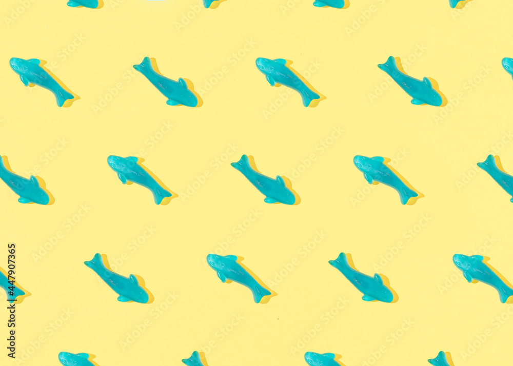 Summer pattern made with blue fish gummy candy on yellow background. Sunny day shadows. Flat lay. Summer pattern made with blue fish gummy candy on yellow background. Sunny day shadows. Flat lay.