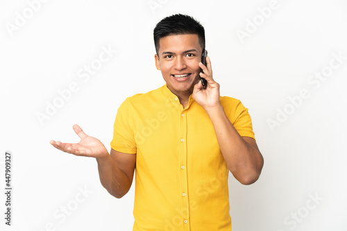 Young Ecuadorian man isolated on white background keeping a conversation with the mobile phone with someone