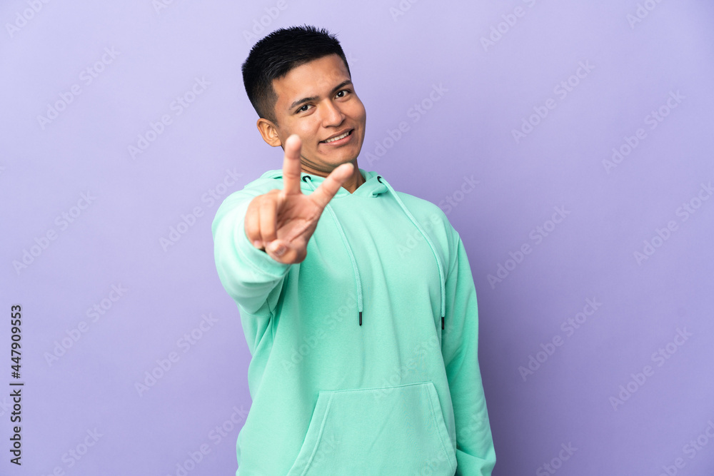 Young Ecuadorian man isolated on purple background smiling and showing victory sign Young Ecuadorian man isolated on purple background smiling and showing victory sign