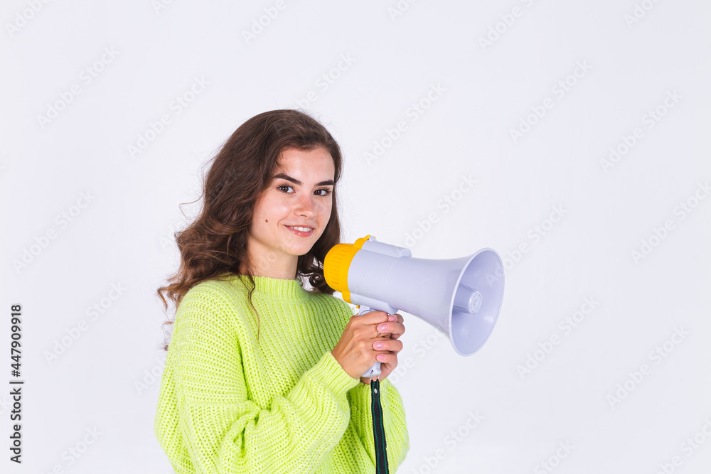 Young beautiful woman with freckles light makeup in sweater on white background with megaphone Young beautiful woman with freckles light makeup in sweater on white background with megaphone
