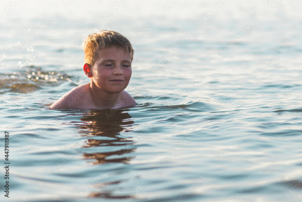 Happy closed eye boy having fun swimming in the water.Cute boy relaxing while swimming in water. Summer vacation.