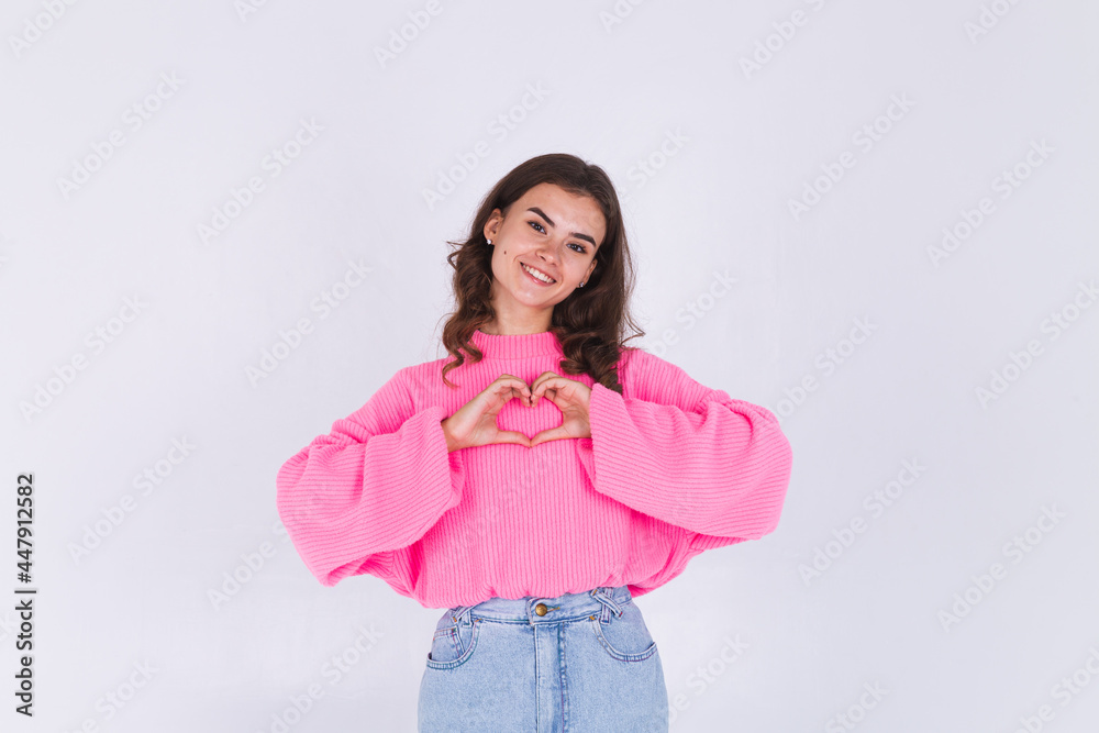 Young beautiful woman with freckles light makeup in sweater on white background shows heart with hands happy cute sweet smile Young beautiful woman with freckles light makeup in sweater on white background shows heart with hands happy cute sweet smile