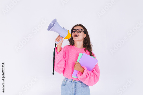 Young beautiful woman with freckles light makeup in sweater on white background student in eye glasses holding megaphone cheerful excited smile