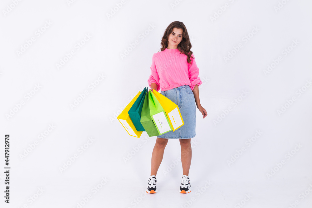 Young beautiful woman with freckles light makeup in pink sweater and jeans skirt on white background stylish full length hold shopping bags