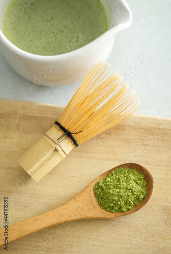 Mixing matcha with wooden spoon and chasen whisk in chawan bowl.