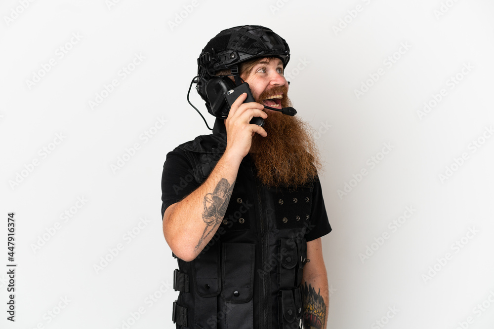 Redhead SWAT isolated on white background keeping a conversation with the mobile phone Redhead SWAT isolated on white background keeping a conversation with the mobile phone